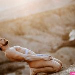 Naked mid adult man kneeling on land at desert during sunset stock photo