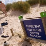 UK Dorset Studland Bay Naturist Beach sign with naked man and discarded clothing Stock Photo